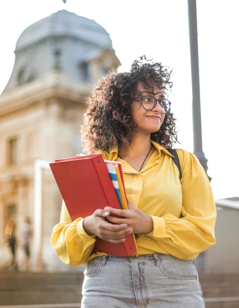 Woman in a yellow jacket holding books