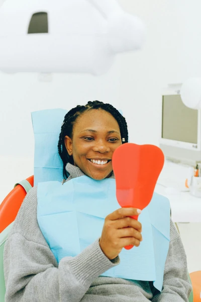 A woman holding a mirror in a dental clinic smiling