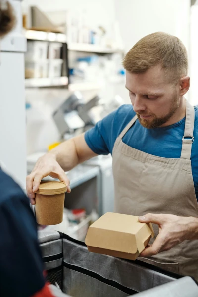 Waiter in an apron holding a cup and box