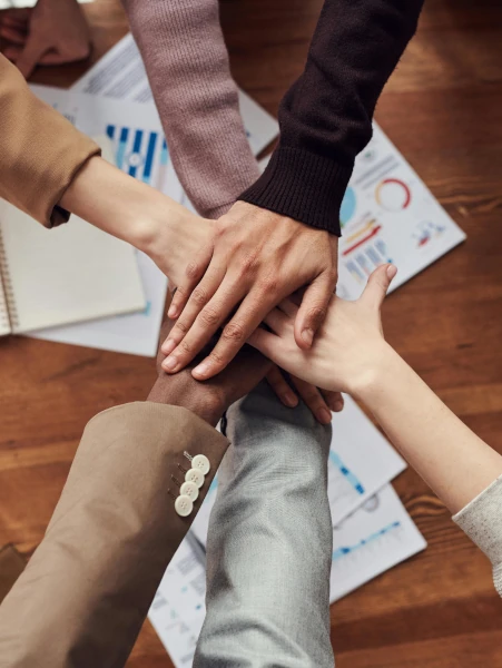 A group of people placing their hands together in the middle of a table